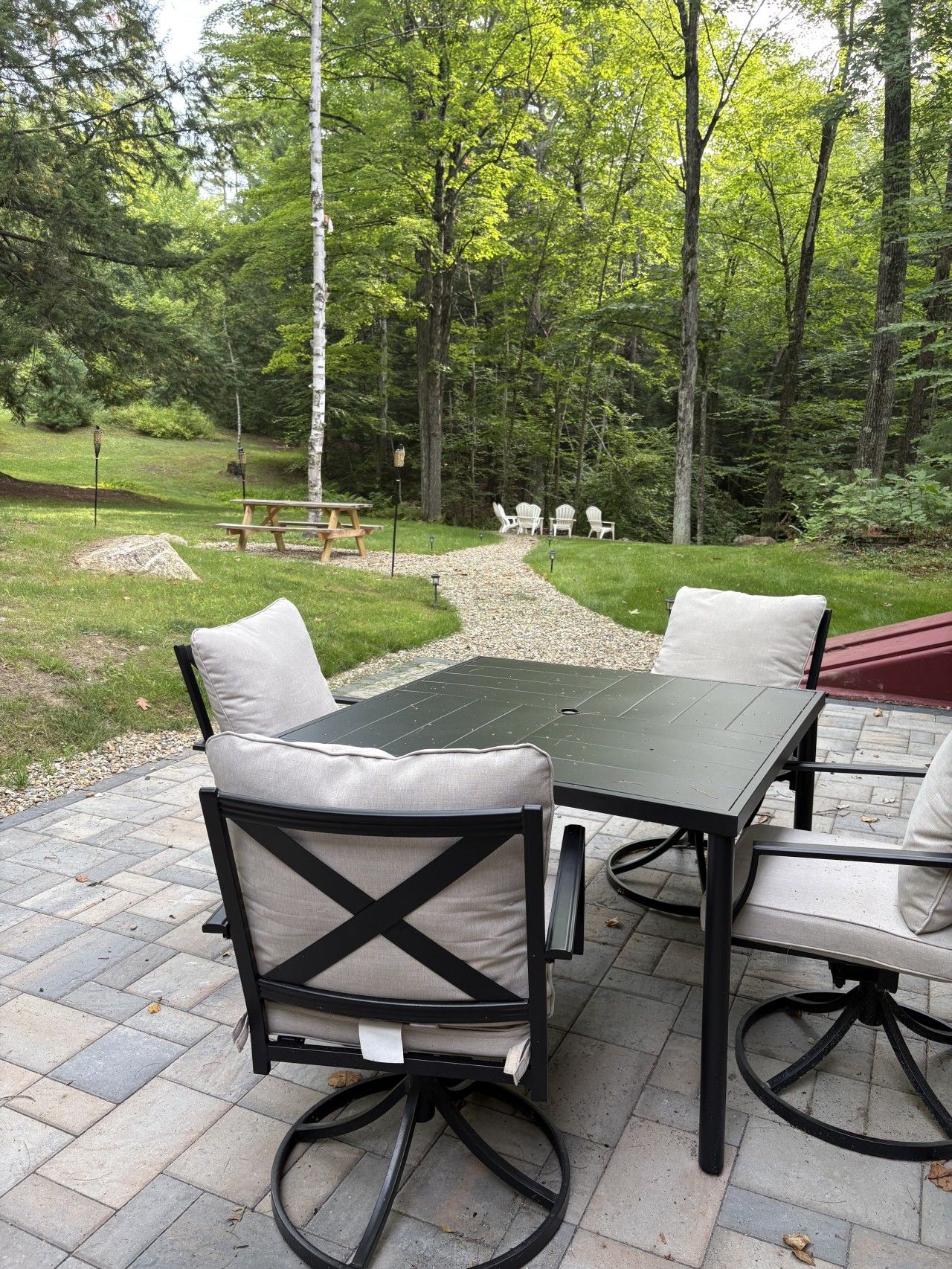 An outdoor patio with a table and chairs, surrounded by a gravel path and greenery.