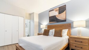 Habitación de hotel con cama, mesitas de noche, cabecera de madera, un cuadro y un armario.