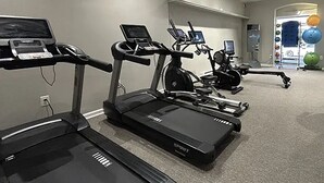 Un gimnasio con cintas de correr, elípticas y una bicicleta estática.