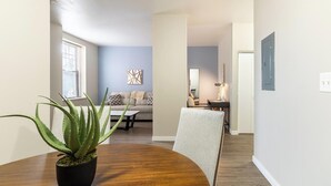 Un comedor con una mesa de madera, una planta en maceta y un sofá al fondo.