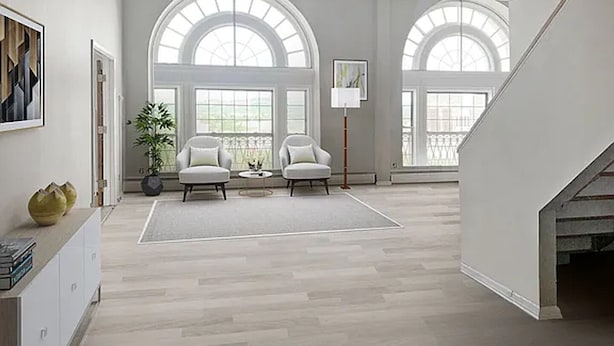 Un salón amplio con techo alto, ventanas grandes y una escalera.