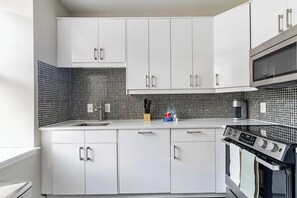 Eine moderne Küche mit weißen Schränken, einer schwarz-weißen Küchenrückwand, einer Edelstahl-Dunstabzugshaube und einem eingebauten Backofen.