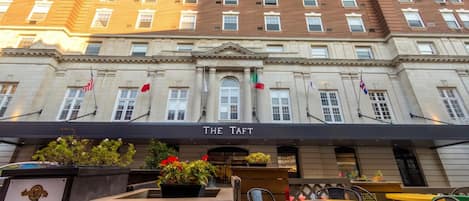 A hotel facade with a sign reading 'THE TAFT' and multiple flags.