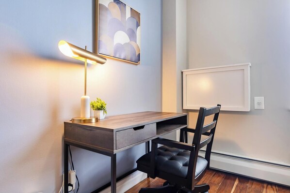 Ein moderner Arbeitsraum mit Schreibtisch, Stuhl und einer Wandlampe.