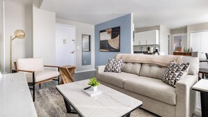 Ein modernes Wohnzimmer mit Sofa, Couchtisch, Sessel und Stehlampe.