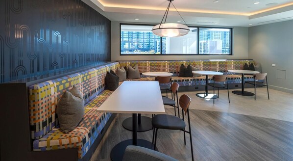 Een moderne lounge met een gestreept bankje, ronde tafels en stoelen.