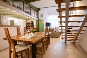 Interior moderno com mesa de jantar de madeira, cadeiras, escada e porta verde.