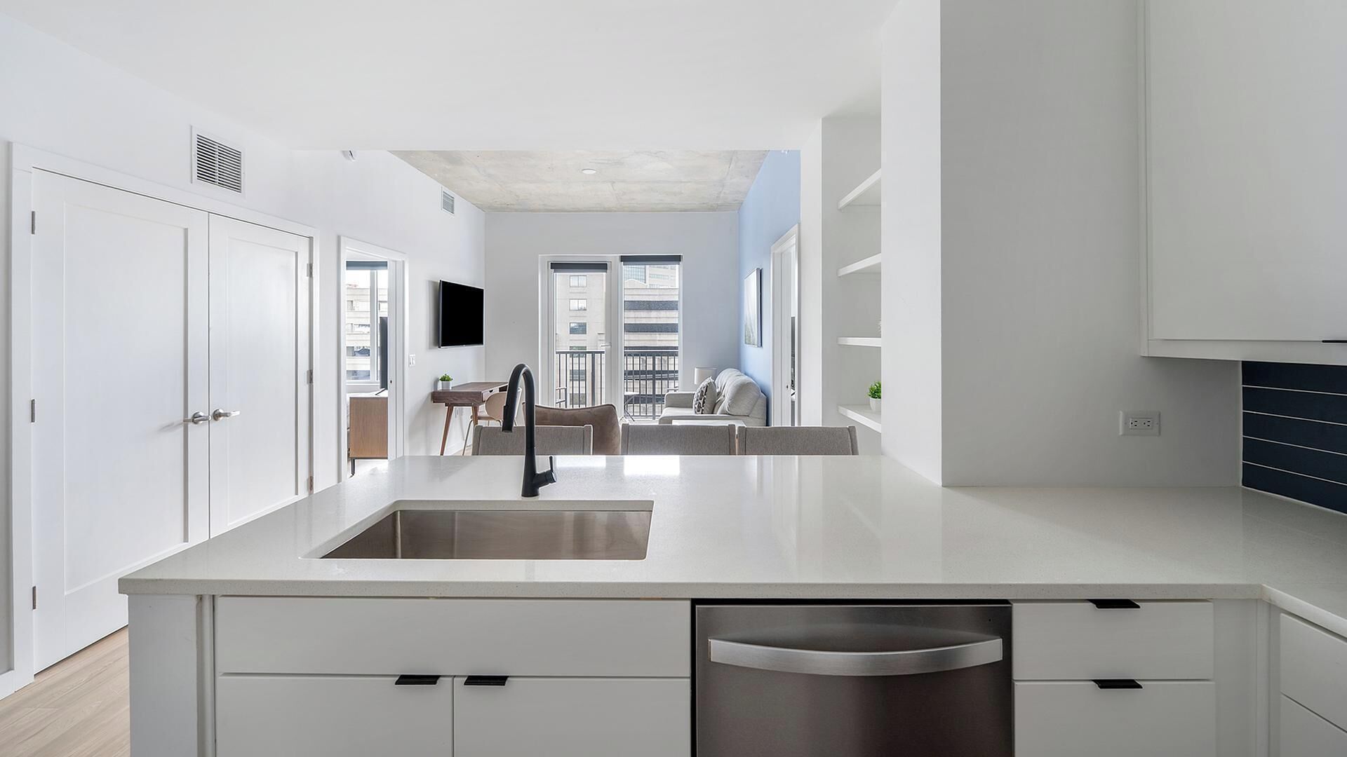 A modern kitchen with a central island, built-in dishwasher, and a dining area with a view to the outside.