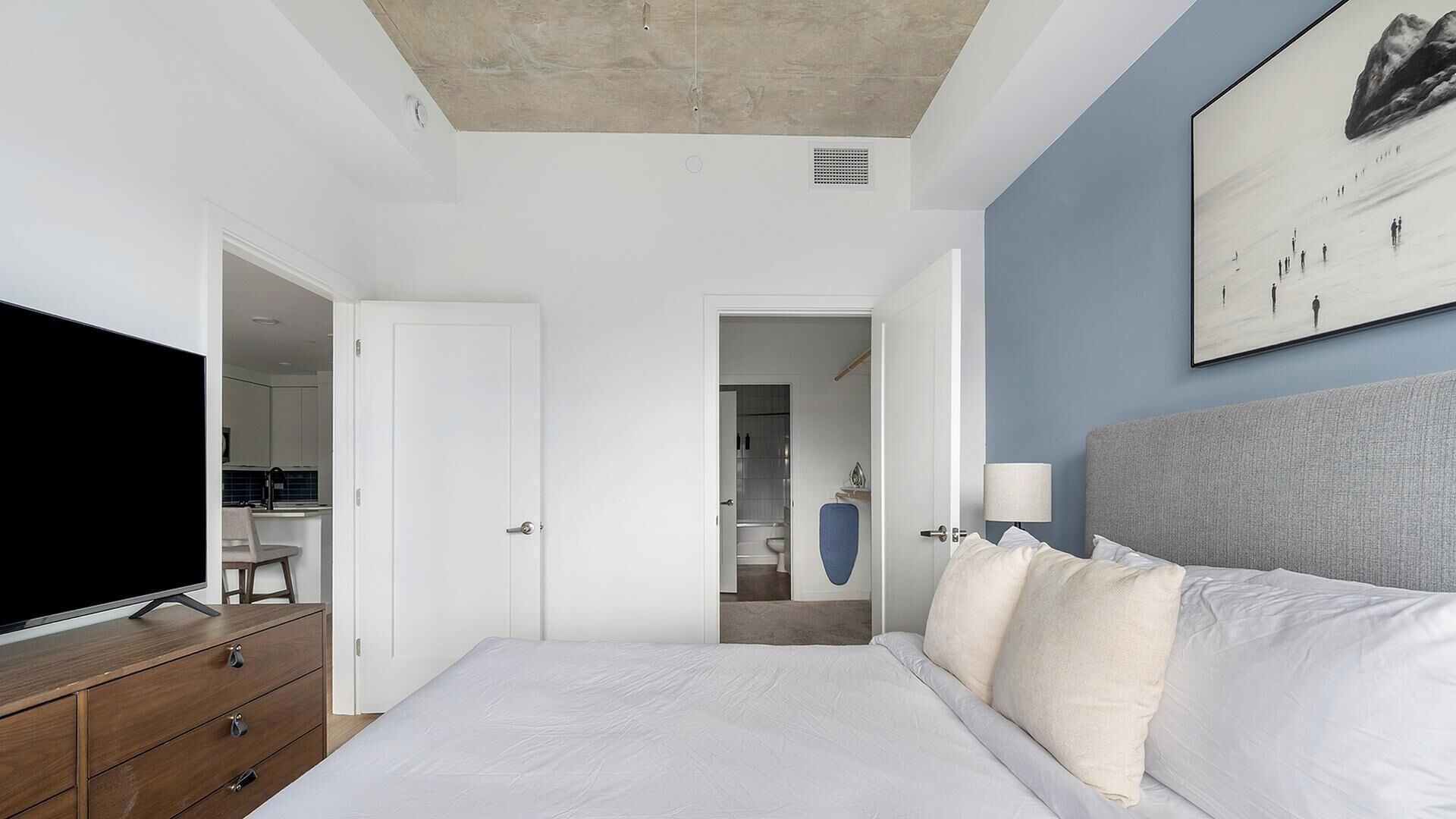 Une chambre à coucher moderne avec un grand lit, une télévision et un tableau au mur.
