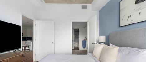 Une chambre à coucher moderne avec un grand lit, une télévision et un tableau au mur.