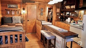 Una habitación acogedora tipo cabaña con una cama de madera, una pequeña kitchenette y una zona de bar.