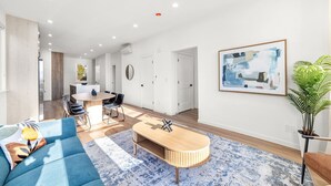 A modern living room with a blue sofa, a wooden coffee table, and a large abstract painting on the wall. - Modern Comfort in Seattle, 10 mins to downtown (Seattle)