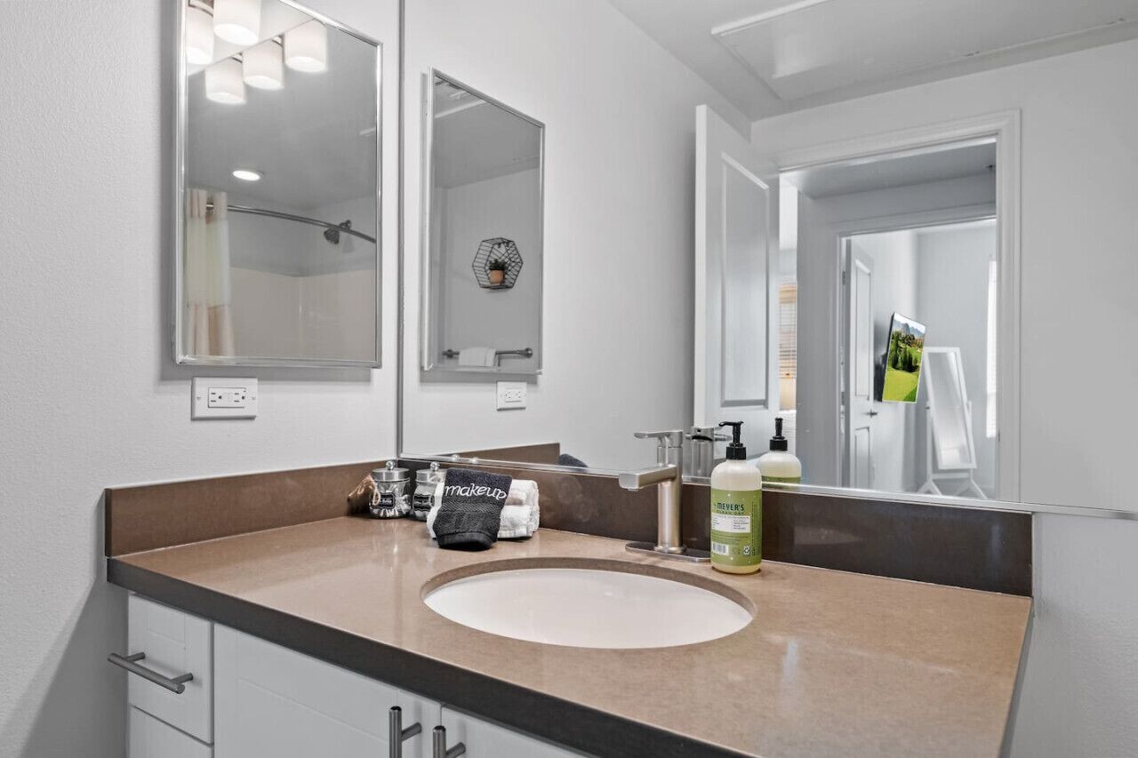 A modern bathroom with a large mirror, a sink, and a towel rack.