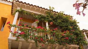 A building with a balcony covered in flowering plants and a yellow facade. - Best location; magical 4BR house w/ large pool (Cartagena de Indias)