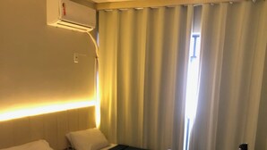 A hotel room with two beds, a chair, and an air conditioning unit. - Condominio Summer Park Bloco i (Brasília)