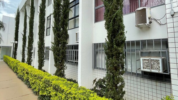 A modern building with a white facade, multiple windows, and air conditioning units. - Condominio Summer Park Bloco i (Brasília)