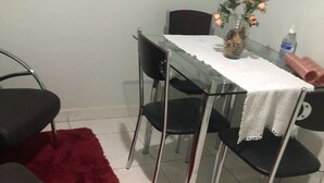 A dining area with a glass table, black chairs, a red rug, and a vase of flowers on the table. - Condominio Summer Park Bloco i (Brasília)