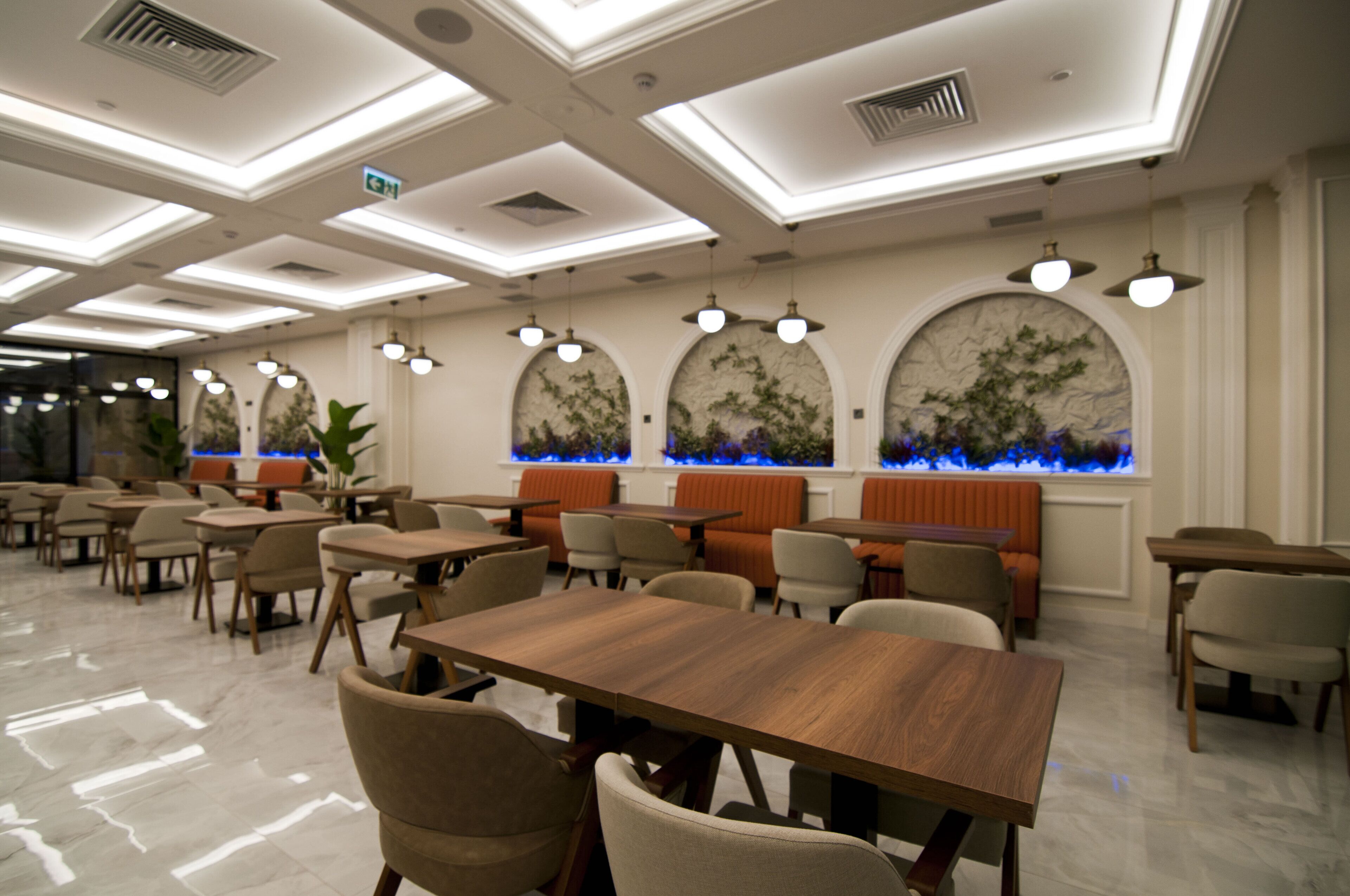 A modern dining area with tables and chairs, recessed lighting, and decorative wall panels.