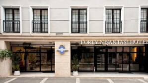 The exterior of the Forty Nisantara Hotel with a prominent entrance, large windows, and potted plants.