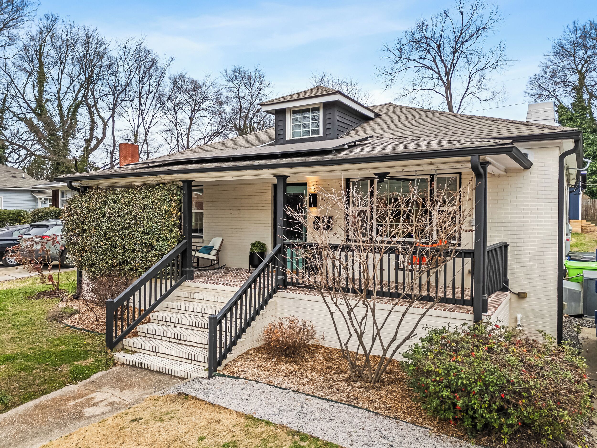 A single-story house with a covered porch, a small front yard, and a garage.