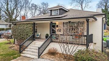 A single-story house with a covered porch, a small front yard, and a garage.