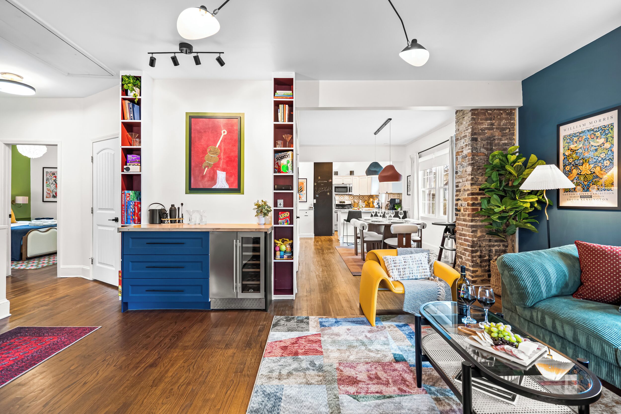 A modern living room with a blue kitchen, a dining area, and a kitchen island.