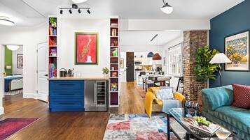 A modern living room with a blue kitchen, a dining area, and a kitchen island.