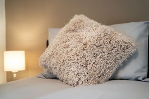 Un letto con un cuscino soffice e strutturato, con una parete chiara sullo sfondo.