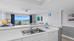 Una cocina moderna con un lavamanos doble, un ventilador de techo y vista a la playa.