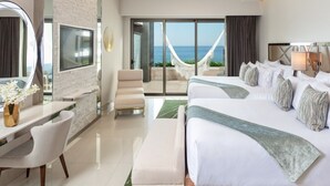 Ein Hotelzimmer mit einem großen Bett, einem Schreibtisch, einem Sessel und einem großen Spiegel, mit Blick auf den Ozean.