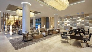 Eine moderne Lobby mit einer zentralen Sitzgruppe, einem Empfangsbereich und einer Wand mit geometrischen Mustern.