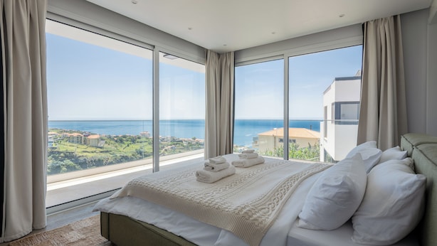 Un dormitorio con una cama grande, vista al mar y un balcón.
