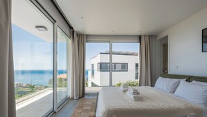 Un dormitorio con una cama grande, vistas al mar y un balcón.