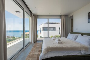 A bedroom with a large bed, a view of the sea, and a balcony. - Sunny Ocean View Villa - Calma (Estreito da Calheta)