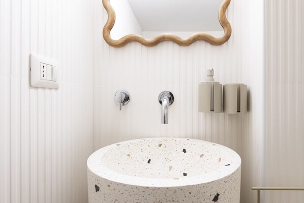 A bathroom with a round sink, a mirror, and a towel dispenser. - Easylife - Milano - Sarpi 6 - Chinatown (Milano)