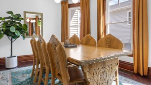 Un comedor con una mesa y sillas de madera, un espejo grande y una planta en maceta.