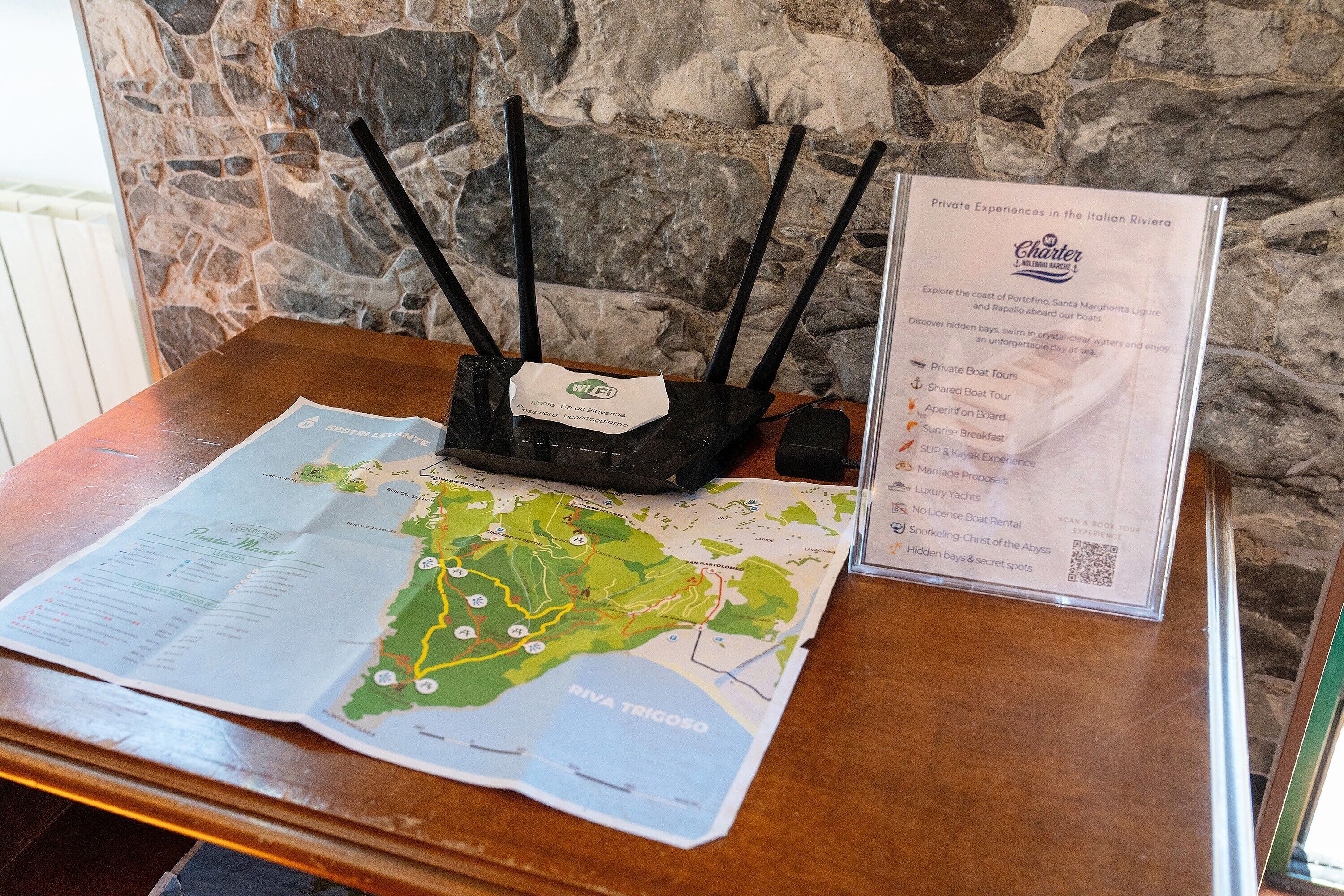 Une table en bois sur laquelle sont posés une carte, un menu et une brochure décrivant en détail les expériences privées proposées sur la Riviera italienne.