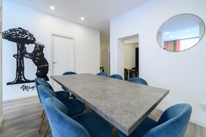 A conference room with a grey table, blue chairs, a wall mural, and a round mirror. - Palacio Real DownTown. 5BR 3BTH. NEW (Madrid)