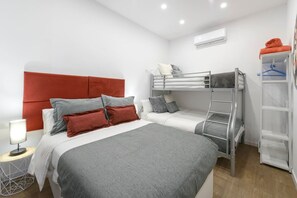 A modern hotel room with two beds, a bunk bed, a bedside table with a lamp, and a wardrobe. - Palacio Real DownTown. 5BR 3BTH. NEW (Madrid)