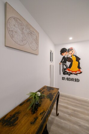 A hallway with a wooden bench, a wall-mounted map, and a mural of a couple with the word 'MADRID' below it. - Palacio Real DownTown. 5BR 3BTH. NEW (Madrid)