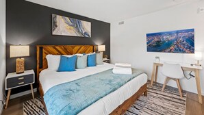 Ett modernt hotellrum med en stor säng, ett skrivbord och utsikt över staden.