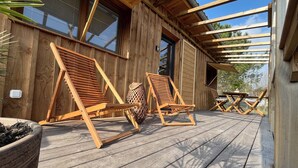 A wooden deck with two wooden lounge chairs and a woven basket.