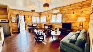 A cozy cabin interior with a wooden interior, a dining area, a sofa, and a television.