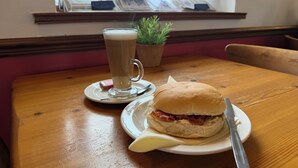 Une table avec un sandwich, un verre de bière et une petite plante en pot.