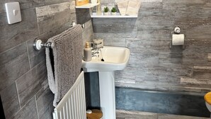 Une salle de bain moderne avec un plancher en bois, un lavabo blanc et un porte-serviettes.