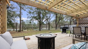 An outdoor deck with a hot tub, seating area, and a grill.