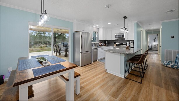 A modern kitchen with a central island, stainless steel appliances, and a dining area with a wooden table and chairs.