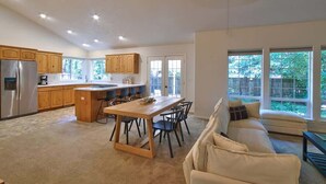 A modern kitchen with wooden cabinets, a stainless steel refrigerator, and a dining area with a wooden table and chairs. - Parkview Place - Wine Country Home with Jetted Tub (McMinnville)