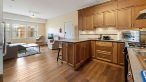 Una cocina moderna con armarios de madera, una isla grande y un comedor con sofá y sillas.