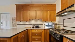 Una cocina con armarios de madera, estufa y microondas.
